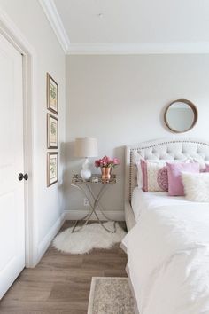 a bedroom with white bedding and pink pillows on top of the bedspread