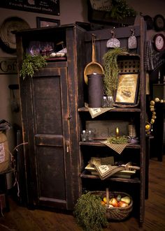 an old wooden cabinet with plants and other items on it's shelves in a room