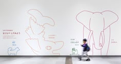 a person walking in front of a wall with drawings on it and an elephant drawn on the wall