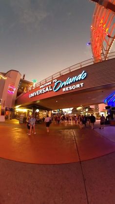 the entrance to universal resort at night with people walking around and onlookers