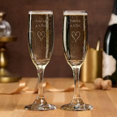 two champagne flutes with hearts on them sitting next to bottles of wine and corks