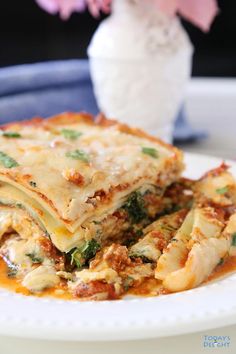 spinach lasagna on a white plate with flowers in the background and text overlay