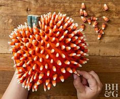 someone is holding a bunch of pencils in front of a large orange ball on a wooden table