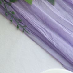 a vase with flowers on a table next to a purple cloth and white bowl filled with water