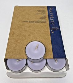 three white candles sitting in a cardboard box