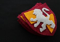 two red and yellow patches with a white lion on it's side, sitting on a black surface