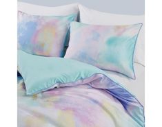 the comforter is made up with pastel blue and purple sheets, along with matching pillows