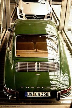 two cars are parked in a garage with stairs leading up to the top and bottom