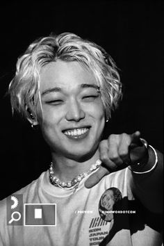 black and white photograph of a woman with her eyes closed smiling at the camera while holding onto a necklace