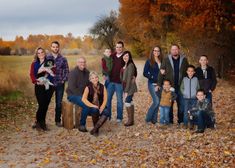 a group of people standing next to each other in front of trees with leaves on the ground