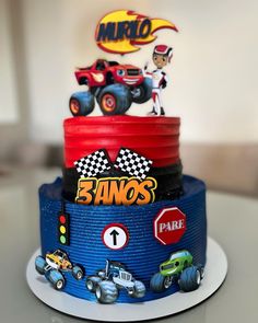 a three tiered cake decorated with cars and race figures on it's side