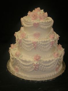 a three tiered wedding cake with pink flowers on top and white icing ruffles