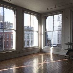 an empty room with wooden floors and large windows