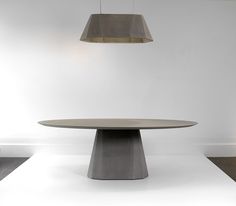 a round table with two pendant lights hanging from it's sides, in front of a white wall