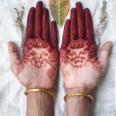 two hands with hendi designs on them and a leaf in the middle one hand