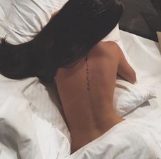 a woman laying in bed with her back turned to the camera and tattoos on her upper half