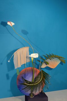 a vase filled with flowers on top of a wooden table next to a blue wall