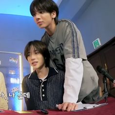 two young men sitting next to each other in front of microphones