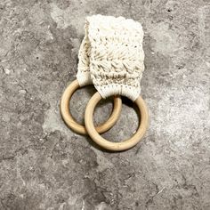 two wooden rings and a white knitted bag on the ground with grey stone flooring