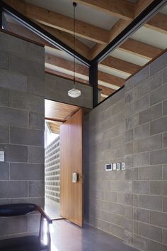 an open door in a room with stone walls and wood ceilinging, along with a black leather chair