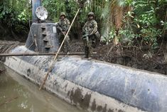 two soldiers standing next to a submarine in the water