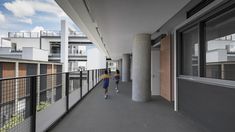 two children are walking down the sidewalk in front of some tall buildings with balconies