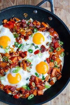 two fried eggs are in a skillet with bacon and green onions on the side