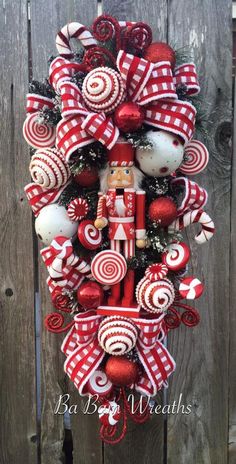 a red and white christmas wreath hanging on the side of a wooden fence with candy canes