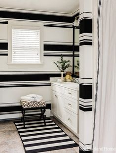 a bathroom with black and white stripes on the walls, flooring and rugs