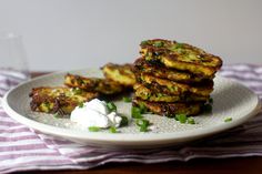 some food is sitting on a white plate with green onions and sour cream around it