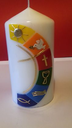 a white candle with different colored designs on it