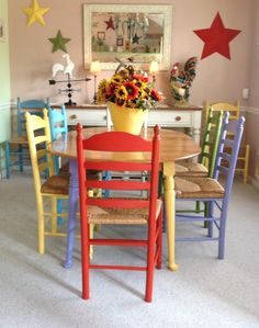 a dining room table with colorful chairs and a potted plant on top of it