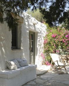 a white couch sitting next to a window on a stone building with flowers in the background