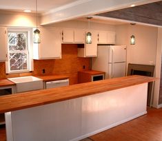 an empty kitchen with white cabinets and wood counter tops