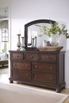 a dresser with a mirror and vases on it next to a rug in a living room