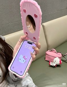 a girl is holding up her phone case with a hello kitty design on the back