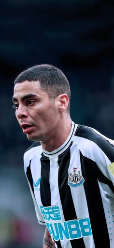 a close up of a soccer player wearing a black and white striped shirt with tattoos on his arm