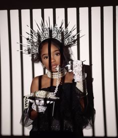 a woman in a black dress holding a tray with pearls and beads on her head