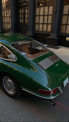 a green car parked in front of a tall building