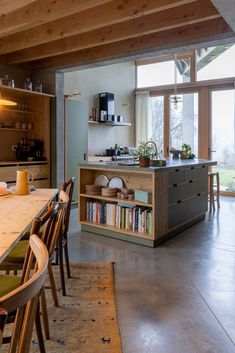 an open kitchen and dining room area with table, chairs, bookshelf and window