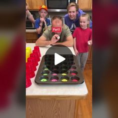 a group of people standing around a cake on top of a table with cupcakes