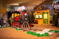 a toy train is on display in a museum like setting with fake trees and rocks