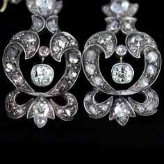 "Georgian silver topped 14k gold drop earrings with over 5 carats of diamonds feature a combination of old mine cut and rose cuts. The stunning earrings have been preserved for nearly 200 years. One has been repaired at some point in its history of ownership. The bottom flourish was reattached and the top of the pendulous was reinforced and reattached. See detailed imagery of repairs. These have not been cleaned by us in case of foil backings on non open backed stone mountings, which were preval Luxury Rose Cut Diamond Chandelier Earrings For Wedding, Formal Rose Cut Diamond Chandelier Earrings, Formal Chandelier Earrings With Rose Cut Diamonds, Elegant Chandelier Earrings With Rose Cut Diamonds, Vintage Rose Cut Diamond Earrings For Formal Occasions, Luxury Rose Cut Diamond Drop Earrings, Luxury White Gold Bridal Earrings With Rose Cut Diamonds, Victorian Bridal Earrings For Anniversary, Ornate Diamond Accent Drop Earrings