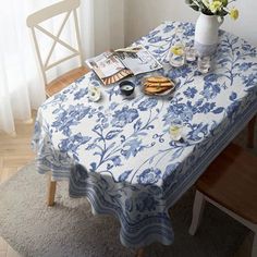 a blue and white table cloth with flowers on it next to a vase filled with flowers