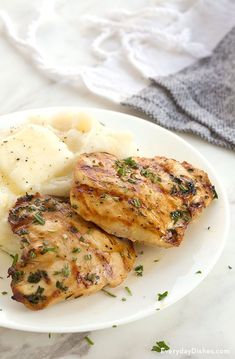 two pieces of chicken and potatoes on a white plate