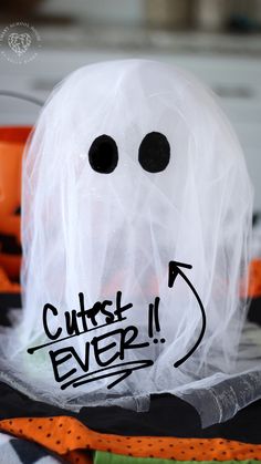 a white plastic ghost with black eyes and words on it's face that says cutest ever