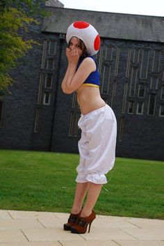 a woman dressed in white and blue is standing on one leg with her hands behind her head