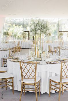 the tables are set up with white linens and gold chairs for an elegant reception