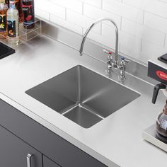 a stainless steel kitchen sink with faucet and soap dispenser