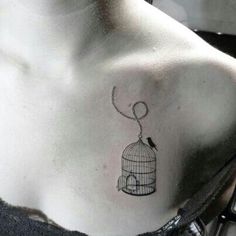 a small bird in a cage tattoo on the back of a woman's chest